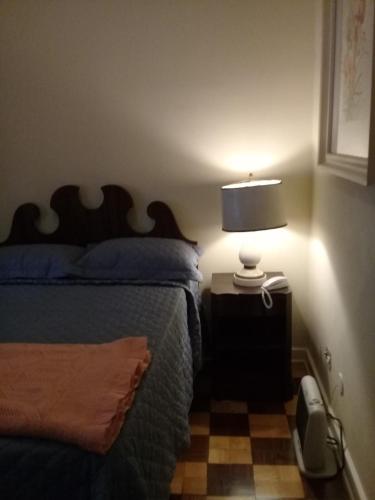 um quarto com uma cama e um candeeiro numa mesa de cabeceira em Palácio Quitandinha 546 em Petrópolis