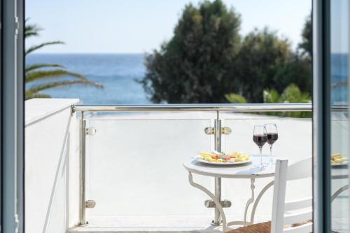 a table with a plate of food and two glasses of wine at Alesahne Beach Hotel in Kamari