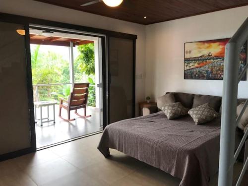 a bedroom with a bed and a balcony with a chair at Villas Lambeau 3 Ocean View - 2BR 3 BA in Uvita