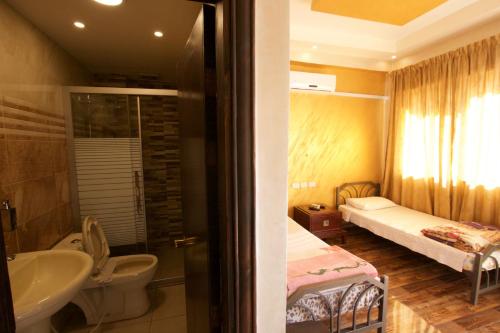 a bathroom with a sink toilet and a bed at Sunrise Hostel in Amman