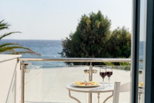 a table with two glasses of wine on a balcony at Alesahne Beach Hotel in Kamari