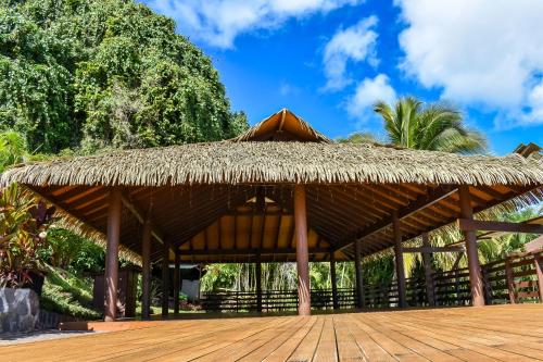 a straw roofed pavilion with a wooden deck at Iro Luxury Retreat in Rarotonga