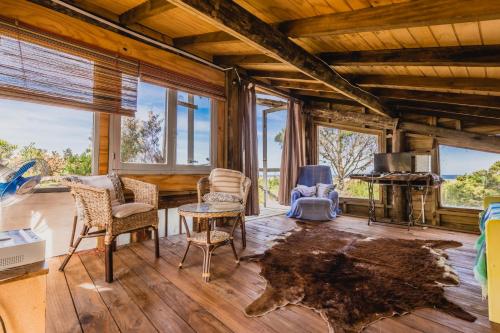 a living room with a table and chairs and windows at La Cabañita de José Ignacio in José Ignacio