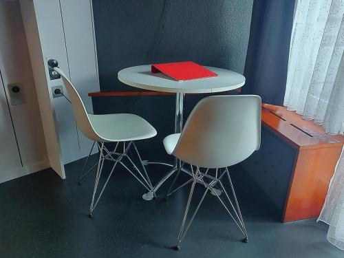a table with two chairs and a red book on it at Z Studio - next door to Vals Therme in Vals