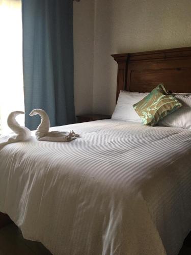 two swans are sitting on a white bed at Hotel Concierge Flor y Canto in Tepoztlán