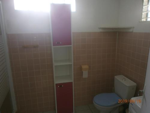 a bathroom with a toilet and a tiled wall at case créole in Pointe-Noire