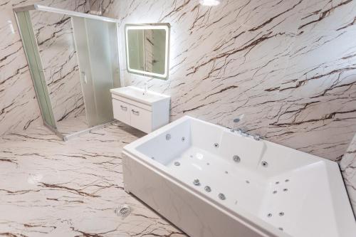 un bagno bianco con vasca e specchio di CITY HOTEL a Ferizaj