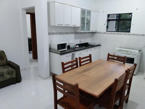 cocina y comedor con mesa de madera y sillas en Apartamentos Praia do Sonho, en Palhoça