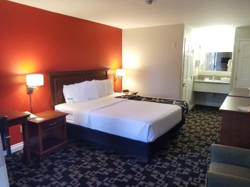 a hotel room with a large bed and a chair at Ramada by Wyndham Oceanside in Oceanside