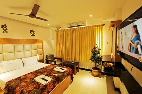 a hotel room with a bed and a flat screen tv at New Cape Hotel in Kanyakumari