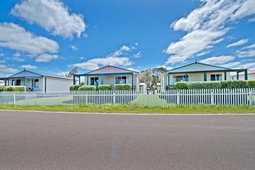 a white and blue house with a fence at Acclaim Rose Gardens Beachside Holiday Park in Albany
