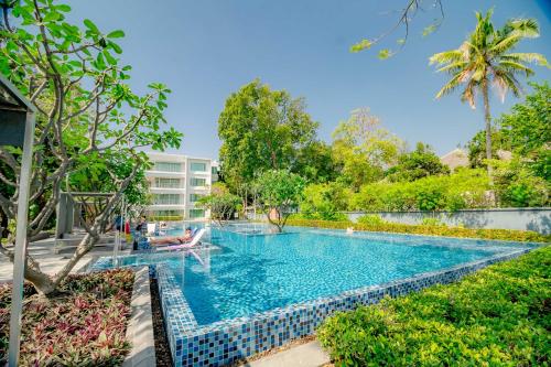 a swimming pool in a resort with a person sitting in a chair in the water at Baan Sandao Condo in Hua Hin