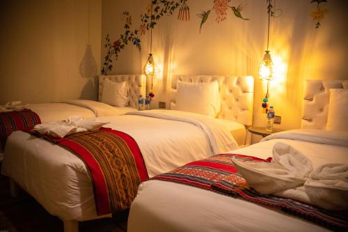 a hotel room with three beds with white sheets at Home Garden Hotel in Cusco