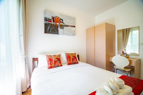 a bedroom with a white bed with red pillows at Baan Sandao Condo in Hua Hin