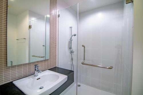 a white bathroom with a sink and a shower at Baan Sandao Condo in Hua Hin