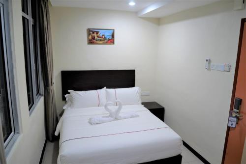 a bedroom with a bed with a white ribbon on it at DCozy Hotel in Perai