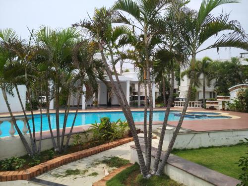 a pool with palm trees in front of a building at Private Luxury Beach Side Villa in Chennai