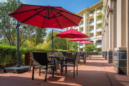 a patio with tables and chairs with red umbrellas at Your World International Conference Centre Hotel in Yiwu