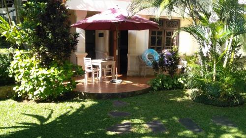 a patio with an umbrella and a table and chairs at Jungle Garden Villa in Mayong
