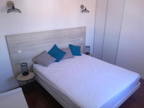 - un lit blanc avec des oreillers bleus dans l'établissement Thalassa T3 Les Sables d'Olonne, à Les Sables-dʼOlonne