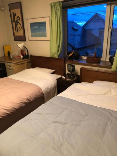una camera d'albergo con due letti e una finestra di Guest House Chara a Hirosaki