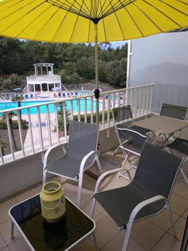 - un balcon avec des chaises, un parasol et une piscine dans l'établissement Thalassa T3 Les Sables d'Olonne, à Les Sables-dʼOlonne