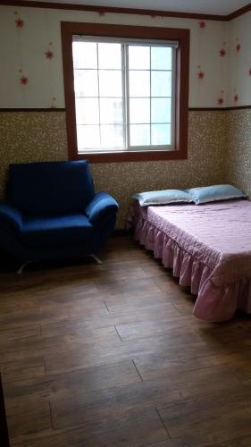a bedroom with a bed and a couch and a window at Daecheon Ocean Hill Pension in Boryeong