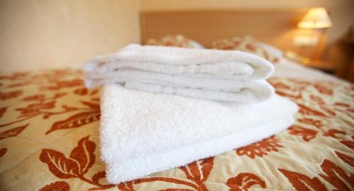 three towels are stacked on top of a bed at Hotel Petit Nord in Hoorn