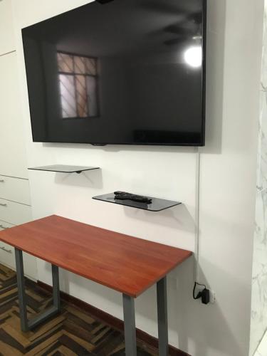 TV colgada en una pared con mesa de madera en Dormitorio Independiente en Lima