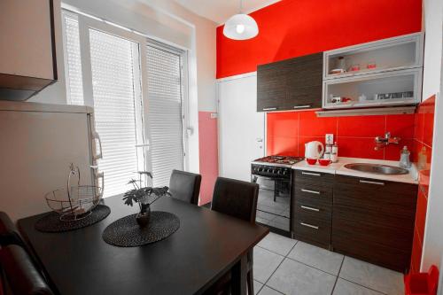 una cucina con pareti rosse e un tavolo con sedie di FLAMINGOS Apartman & Fitness OSIJEK - blizina Bolnice KBC Osijek a Osijek