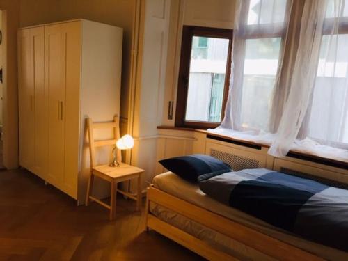 a bedroom with a bed and a chair and a window at Apartment Marktplatz in Basel