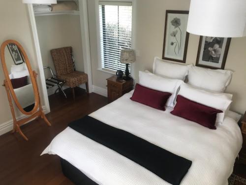 a bedroom with a large white bed with red pillows at Pinot Villas in Martinborough 