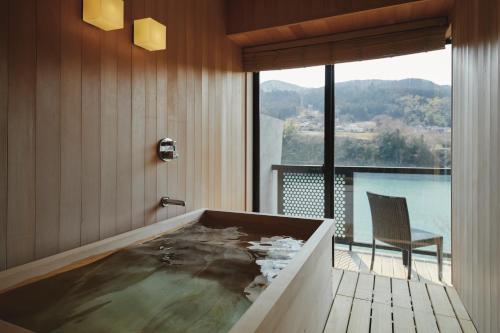 a bath tub in a room with a large window at River Retreat Garaku in Toyama