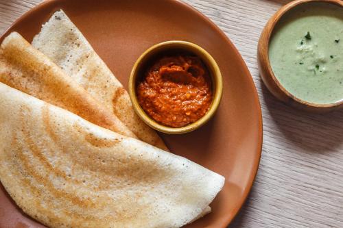 a plate of food with a bowl of dip and bread at Misty Meridian Serviced Apartments in Bengaluru