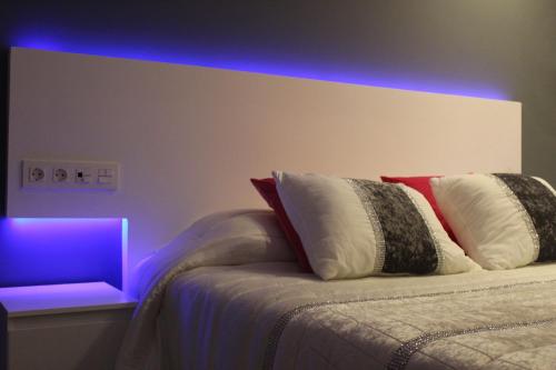 Bilbao Place في بلباو: غرفة نوم مع سرير مع ضوء أرجواني عليه