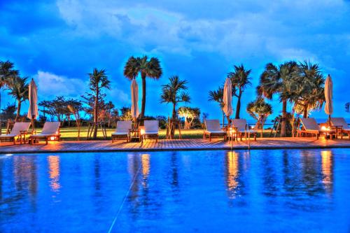 a pool with chairs and palm trees at night at Cypress Resort Kumejima in Kumejima