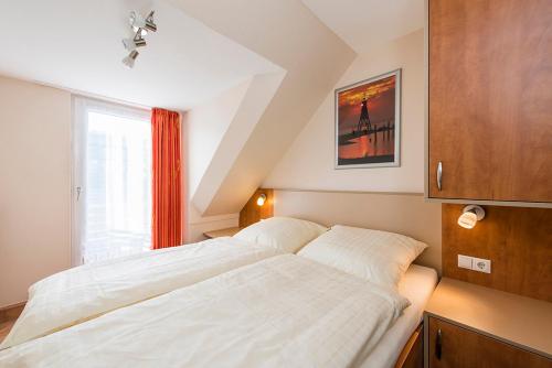 1 dormitorio con 2 camas blancas y ventana en Haus Dünenglück Whg. 34, en Cuxhaven