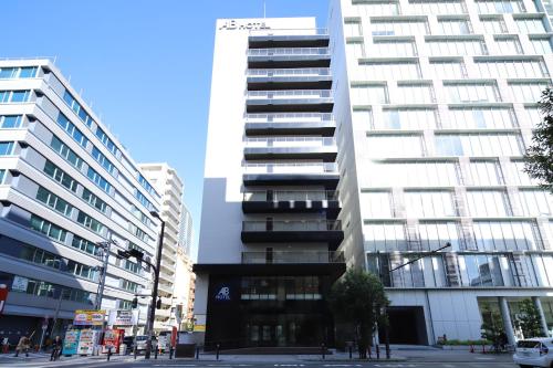 a tall white building in a city with buildings at AB Hotel Osaka Sakaisuji Hommachi in Osaka