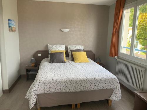 a bedroom with a bed with yellow and gray pillows at Hotel la piscine in Villers-sur-Mer
