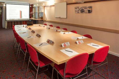 a conference room with a large table and red chairs at ibis Toulouse Centre in Toulouse