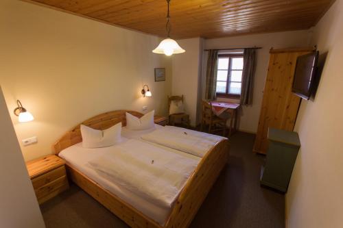 a bedroom with a large bed with white sheets at Landhaus Griessee in Obing