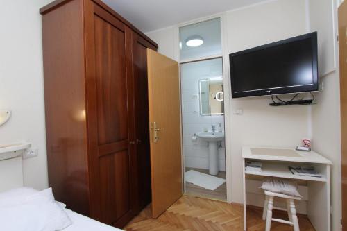 a bedroom with a television and a desk with a sink at Room Roma in Rovinj