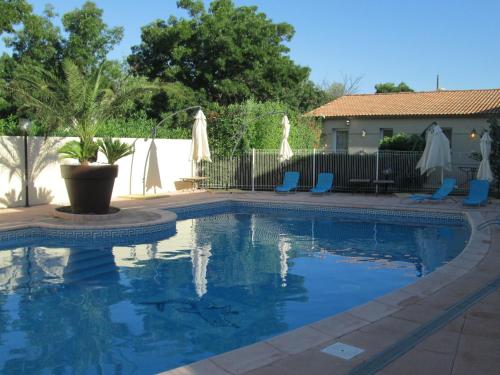 a swimming pool with chairs and umbrellas in a yard at Top Motel in Istres