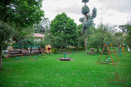 un parque con parque infantil con columpios, mesas y árboles en Hotel Kodai International en Kodaikānāl