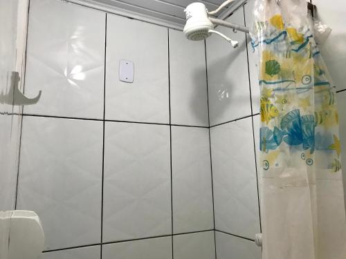 a bathroom with white tiled walls and a shower at Kitnets da vana in Morro de São Paulo
