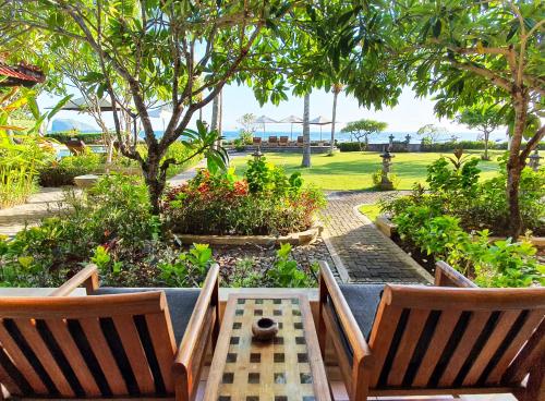 a patio with two chairs and a table and trees at Hotel Genggong in Candidasa