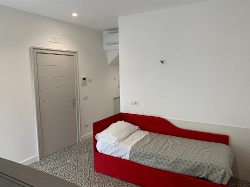Cama roja en habitación blanca con puerta en La casa di Nonna Rosa, en Sant'Agnello