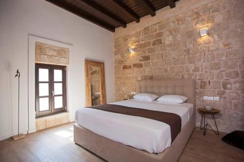 ein Schlafzimmer mit einem großen Bett und einer Ziegelwand in der Unterkunft Casa Quindici in the Old Town in Rhodos (Stadt)
