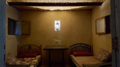 a room with two beds and a table in it at Wadi Ghwere Camp مخيم وادي الغوير in Al Khuraybah