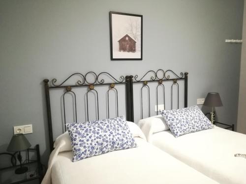 1 dormitorio con 2 camas y almohadas blancas y azules en El Balcón del Duero 1—2, en Castronuño